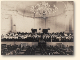 Podium van de grote concertzaal van De Harmonie in Groningen, omstreeks 1908, met groot koor en symfonieorkest onder leiding van Peter van Anrooy